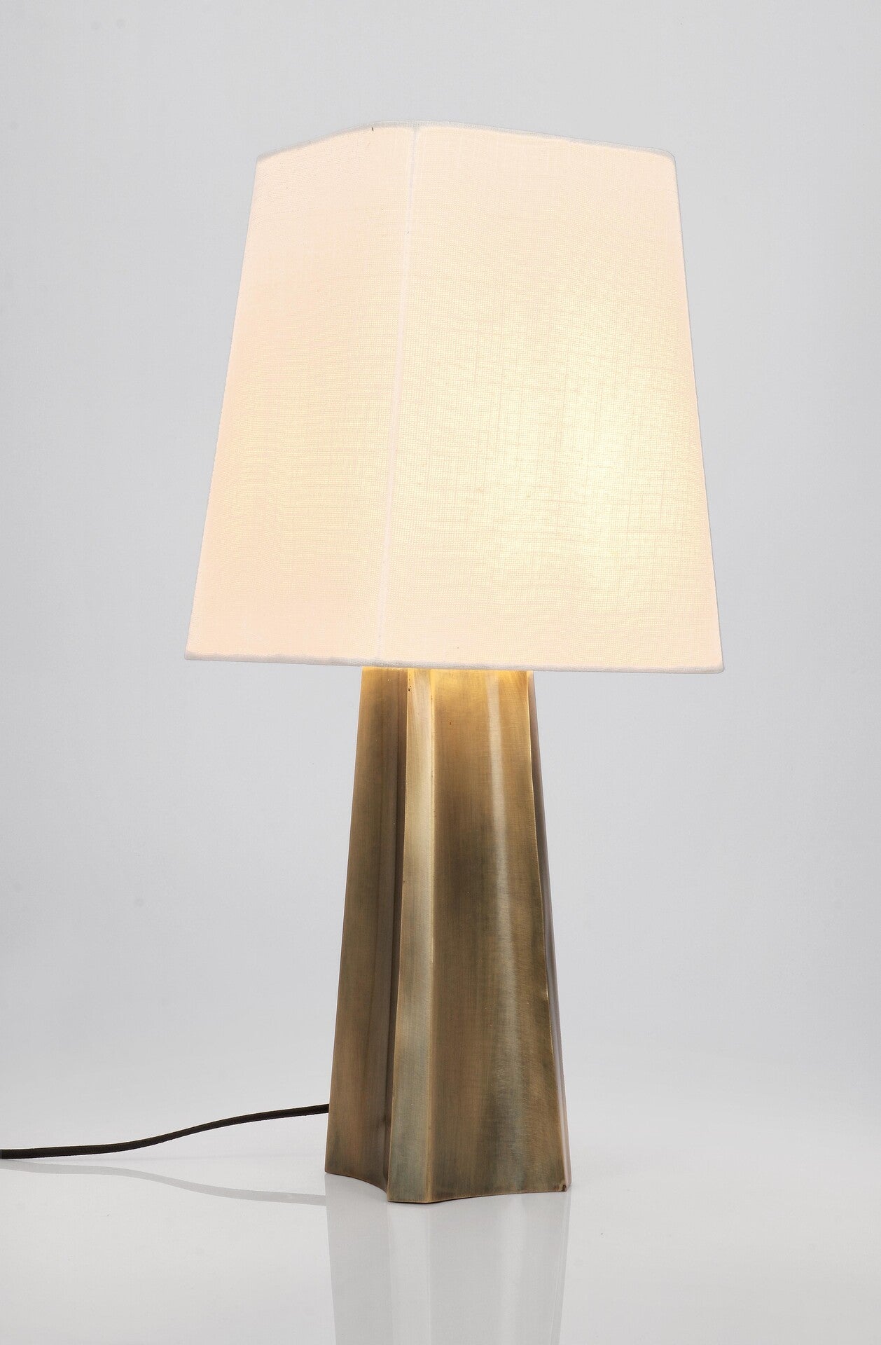 Candeeiro de mesa Tripura com base em metal dourado antigo e abajur branco elegante.